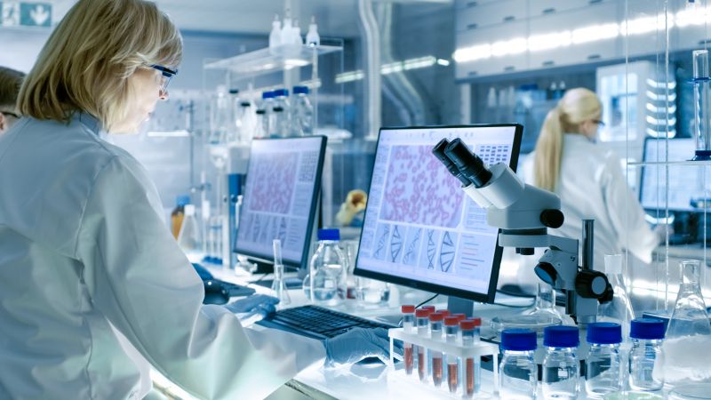 Photo; woman with smock in a medical laboratory in front of a screen