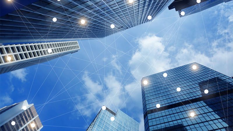 Image: tall office buildings connected via graphic networking lines