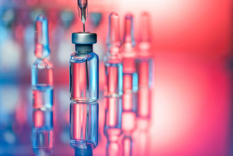 Photo; a syringe removes fluid from an ampoule, close-up